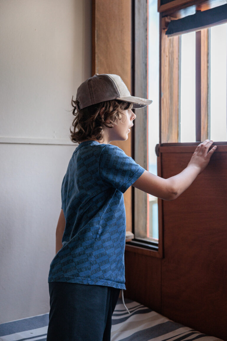 Jeune garçon observant la vue sur la mer méditerrané depuis une fenêtre de la visite de la Villa E-1027
