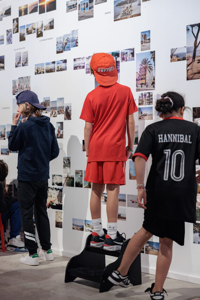 Groupe d'enfants observants un mur sur lequel se trouvent des photos