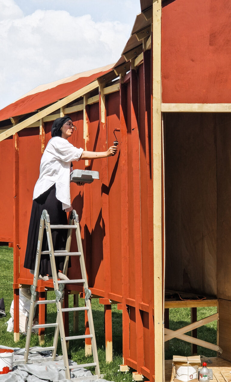 Étudiante architecte en train de peindre un pavillon en bois