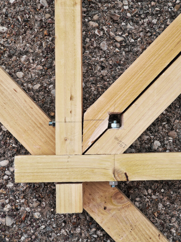 Bastaing en bois en train d'être assemblé sur un sol en béton