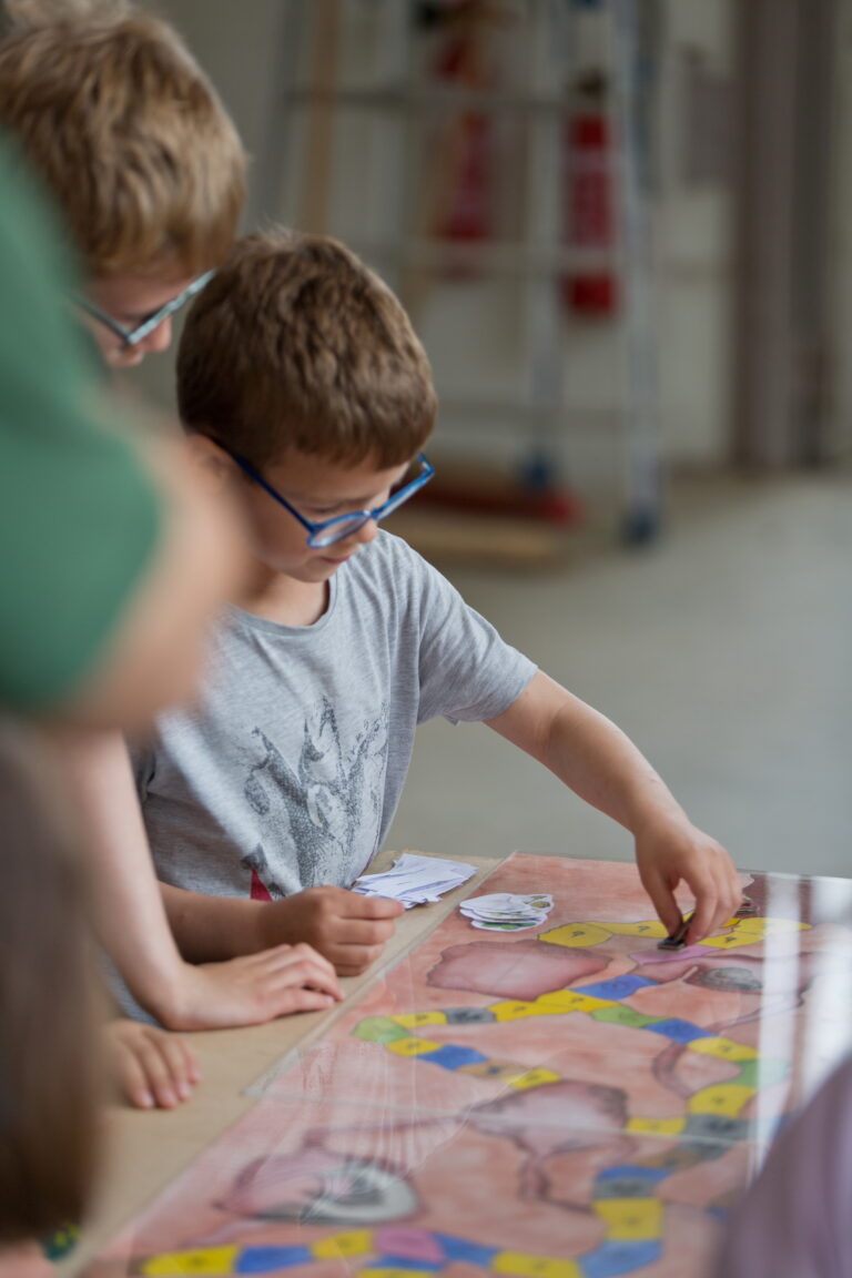 Jeune garçon en train de jouer à un jeu de société avec ses camarades.