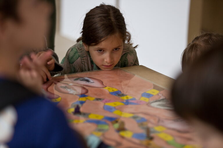 Une jeune fille qui a un regard concentré sur le jeu de société auquel elle participe.