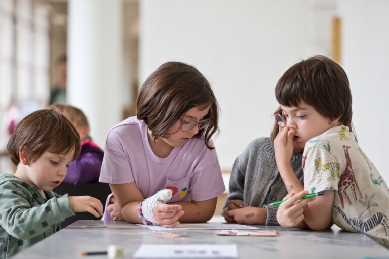 Groupe de jeunes enfants étudiant un document à leur disposition sur une table.