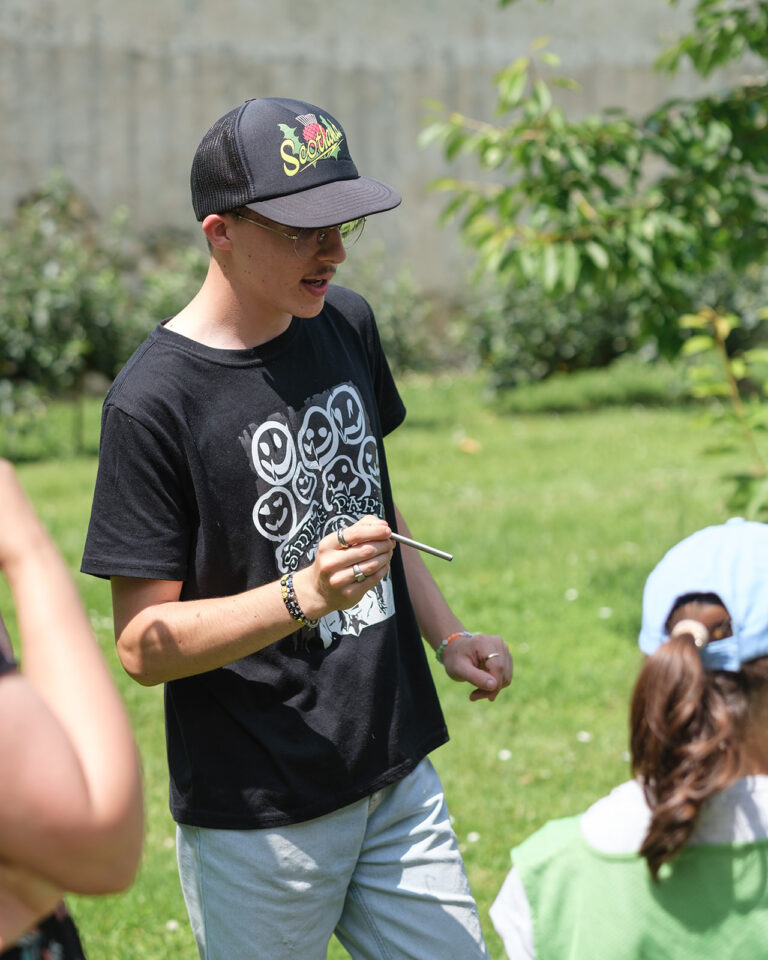 Jeune homme avec une casquette en train de parler à un groupe de jeunes enfants.