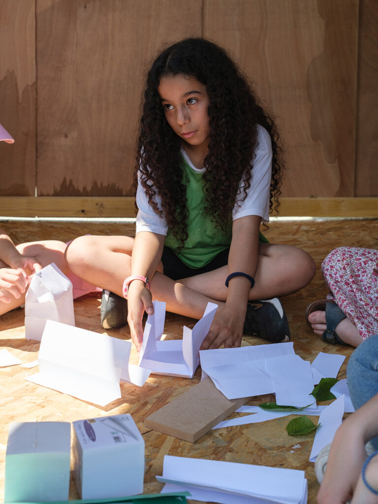 Jeune fille en train de faire une structure en papier.