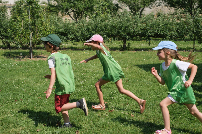 Trois jeunes enfants courant dans un jardin à Versailles, entouré d'arbre fruitier.