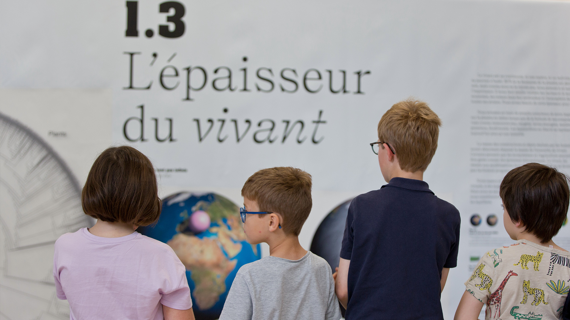 Un groupe de jeunes enfants qui regardent une infographie sur un mur.